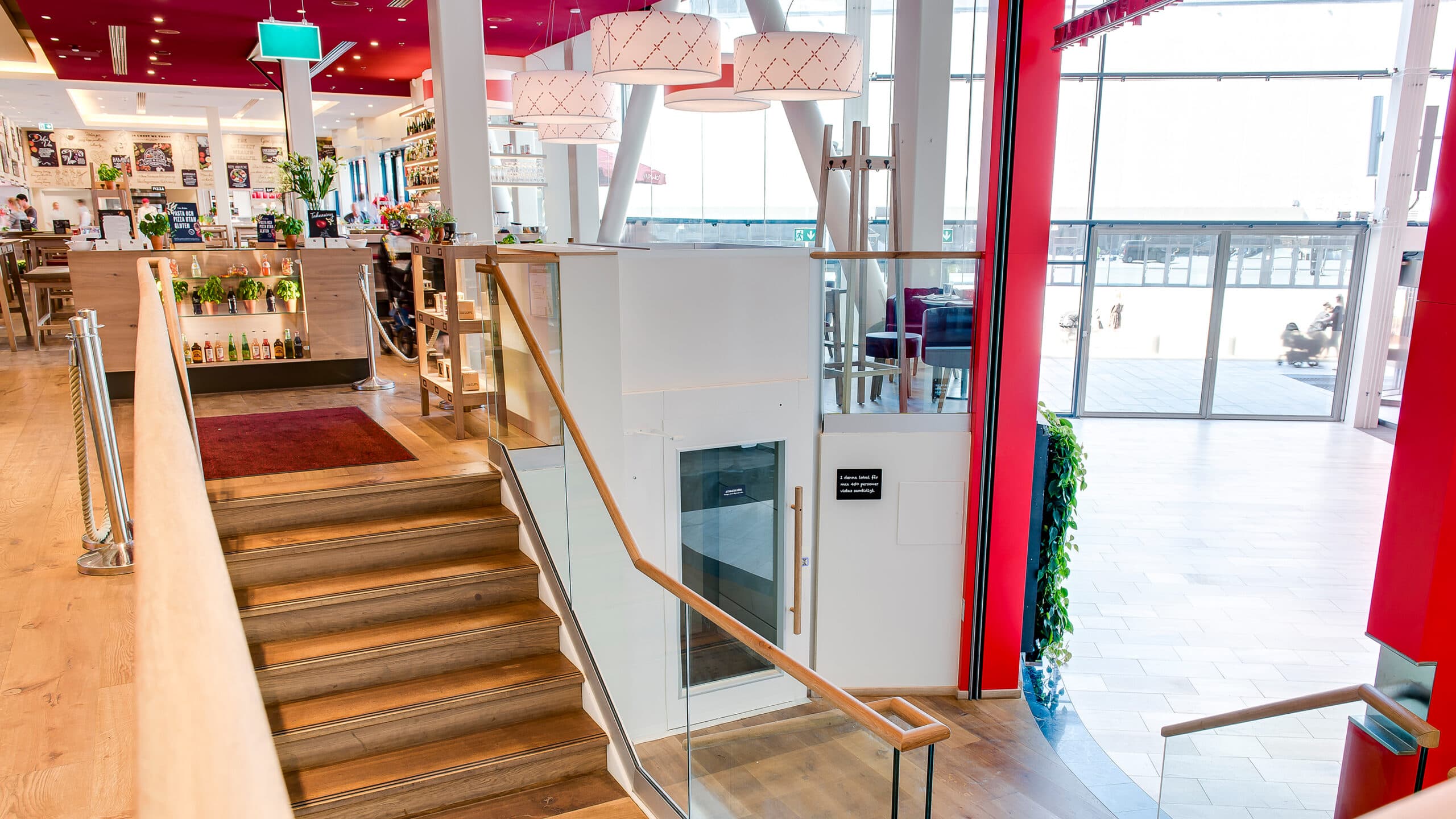 White Cibes Primo commercial elevator, with gate on the top floor, installed in a shopping mall restaurant.